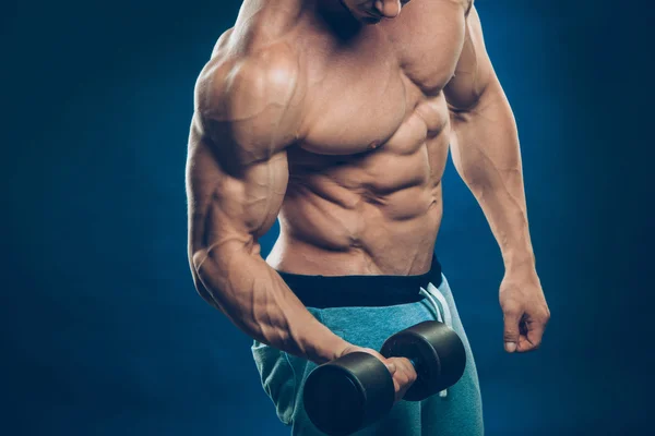 Primer plano de un joven musculoso levantando pesas de pesas sobre fondo oscuro — Foto de Stock