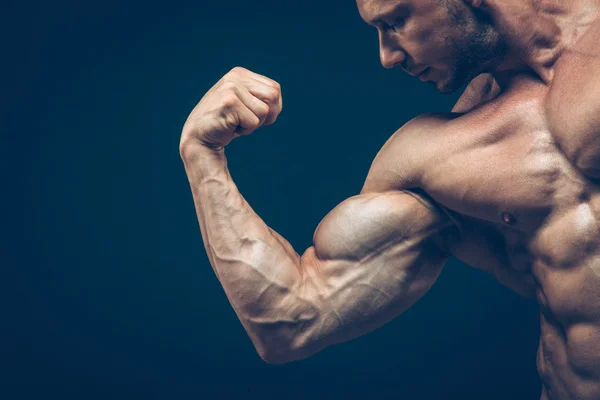 Der Athlet zeigt seinen schönen Körper auf schwarzem Hintergrund. — Stockfoto