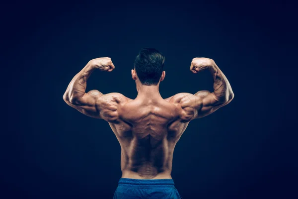 Hombre musculoso posando en estudio oscuro sobre fondo negro . —  Fotos de Stock