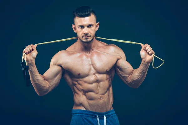 Muskulöser Mann beim Seilspringen. Porträt muskulöser junger Männer, die mit Springseil auf schwarzem Hintergrund üben — Stockfoto