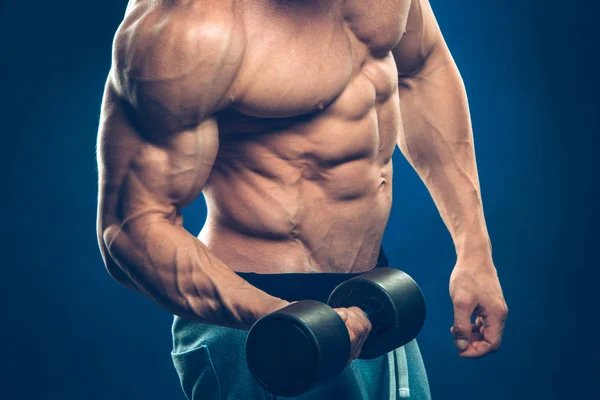 Closeup of a muscular young man lifting dumbbells weights on dark background — Stock Photo, Image