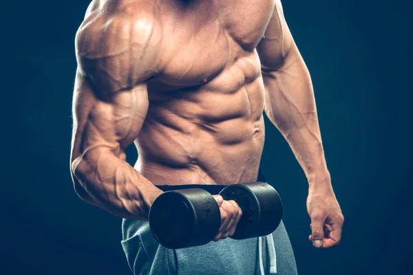 Closeup of a muscular young man lifting dumbbells weights on dark background — Stock Photo, Image