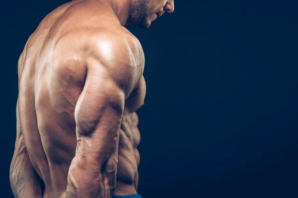 Strong athletic man back on dark background — Stock Photo, Image