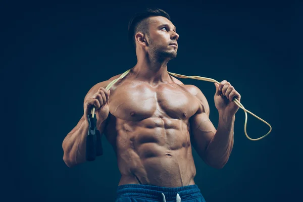 Homem musculoso a saltar corda. Retrato de jovens musculosos exercitando com corda de salto no fundo preto — Fotografia de Stock