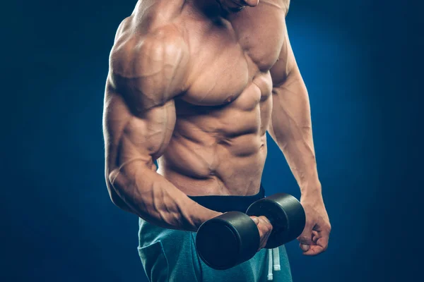 Closeup of a muscular young man lifting dumbbells weights on dark background — Stock Photo, Image