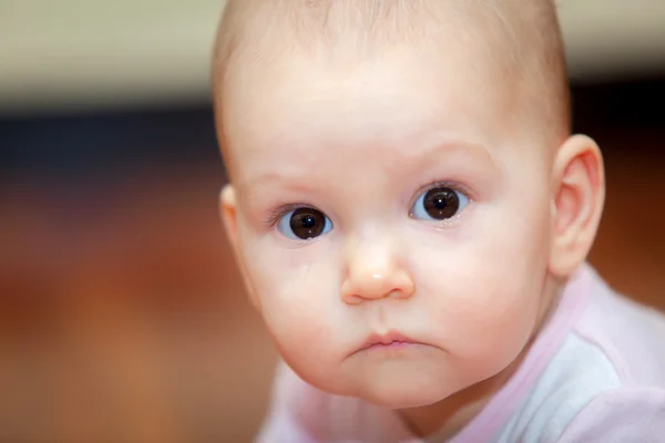 Close-up de uma criança pequena que chora, mas não grita. Uma lágrima a rolar pela bochecha abaixo. Fundo desfocado. Foto menina . — Fotografia de Stock