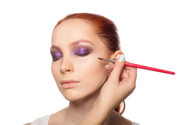 Professional Make-up artist gör glamour med rött hår modell makeup. Isolerade bakgrund. — Stockfoto