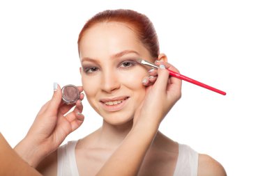 Profesyonel makyöz seksi kırmızı saç modeli makyaj yapıyor. İzole arka plan.