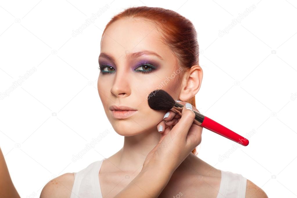 Professional Make-up artist doing glamour with red hair model makeup.  Isolated background.