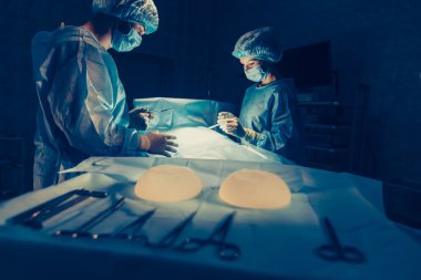 Cerrahlar ekibi cerrahi ameliyathane hastada izleme ile çalışıyor. Göğüs büyütme