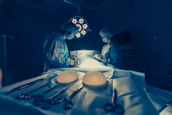 Equipo de cirujanos trabajando con Monitoreo del paciente en quirófano quirúrgico. aumento de senos —  Fotos de Stock