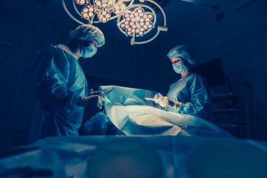 Cerrahlar ekibi cerrahi ameliyathane hastada izleme ile çalışıyor. Göğüs büyütme