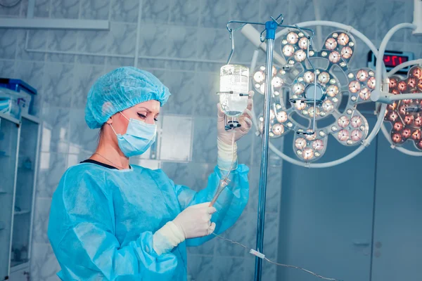 Sjuksköterska justera infusion flaska med mot bakgrund av o — Stockfoto