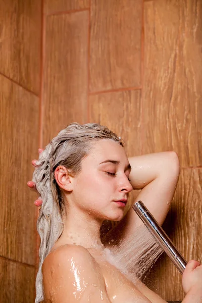 Mulher bonita de pé no chuveiro. Ela segura no chuveiro da mão — Fotografia de Stock