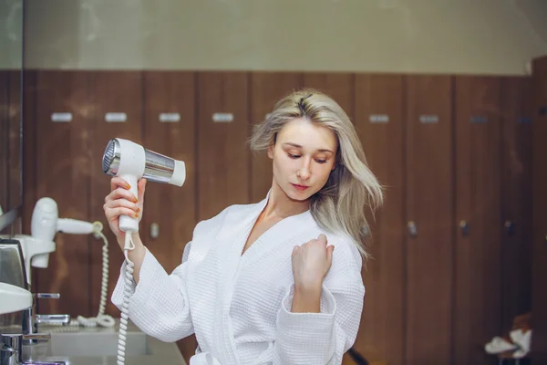 Frau trocknen Haartrockner im Badezimmer. Weibchen mit Trockner nach Hause — Stockfoto