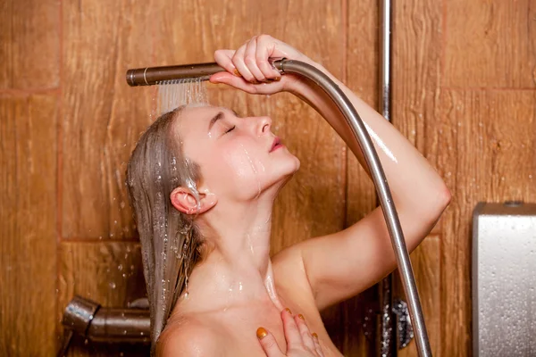 Mulher bonita de pé no chuveiro. Ela segura no chuveiro da mão — Fotografia de Stock