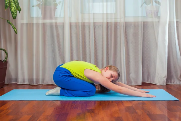fitness. sport, training and lifestyle concept - Child doing exercises on mat in home.