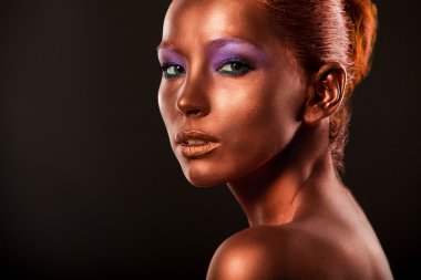 Gilt. Golden Womans Face Closeup. Futuristic Gilded Make-up. Painted Skin bronze.
