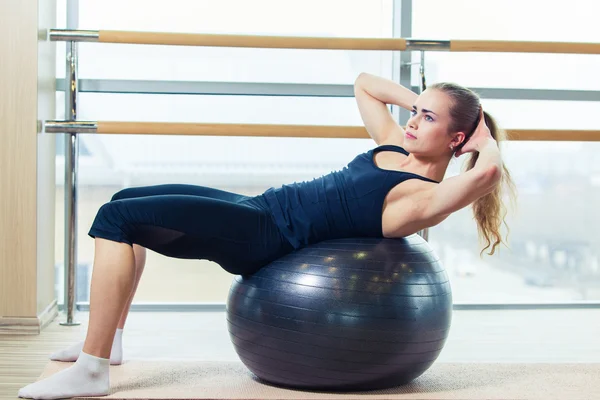 Ung glad kvinna göra fitnessövningar med fit boll hemma — Stockfoto