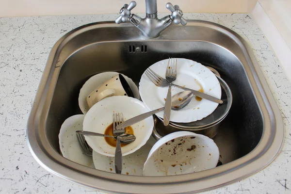Dirty dishes: plates, cup, forks, spoons in the sink