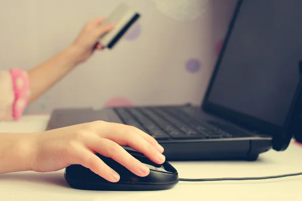 Close up of female hand on computer mouse and holding a credit card. The concept of online shopping.