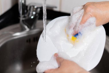 Kız mutfakta bulaşık yıkıyor, beyaz tabak yıkıyor. Yüksek kalite fotoğraf