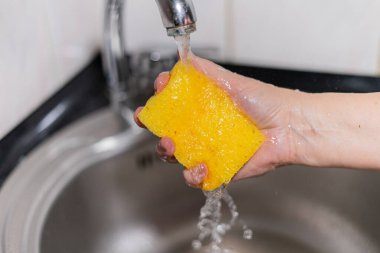 Suyun altındaki bulaşıklar için sarı sünger. Yüksek kalite fotoğraf