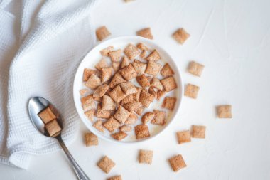 Beyaz beton arka planda sütlü kahvaltılık gevrek pedleri 