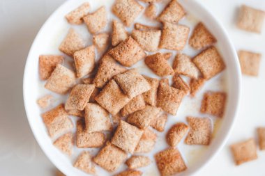 Beyaz beton arka planda sütlü kahvaltılık gevrek pedleri 