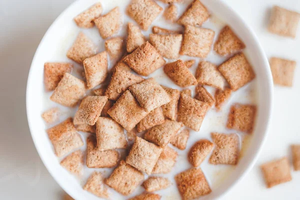 Almofadas de cereal de café da manhã seco com leite em um fundo de concreto branco — Fotografia de Stock