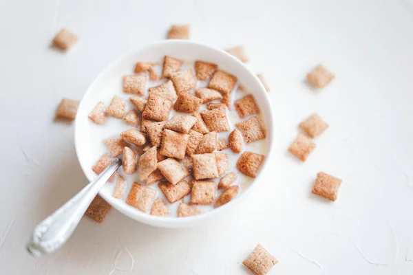 Almofadas de cereal de café da manhã seco com leite em um fundo de concreto branco — Fotografia de Stock