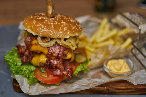 Pyszny burger z podwójnym kotletem i frytkami na drewnianej desce — Zdjęcie stockowe