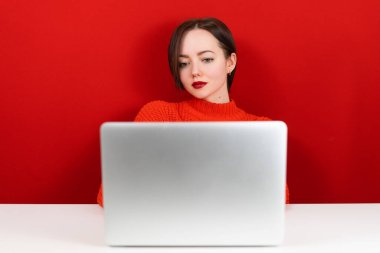 Bilgisayarın başındaki güzel kız kırmızı arka planda.