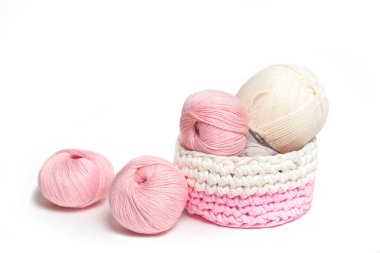 Beyaz yalıtımlı arka planda pembe ve beyaz yün iplikler. İplikle örülmüş sepet.