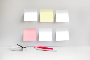 İş yerinin parlak bir odadaki fotoğrafı. Yapışkan kare banknotlar duvara yapışmış. İş yerinde defter ve kalemler var. Asgari tasarım