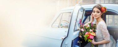 Gelinin portresi mavi bir arabada ve elinde bir buketle.