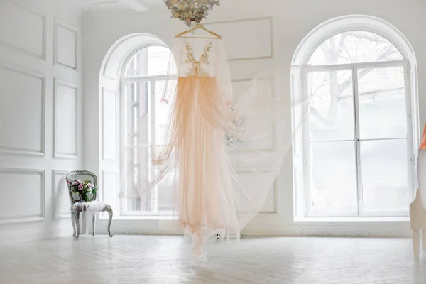 Classic white interior with large windows. Wedding dress in the center of the room