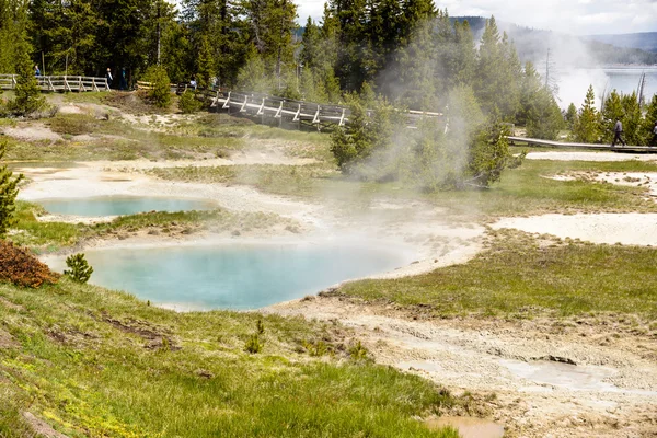 Steaming aqua hot spring, with people on boardwalk, Yellowstone.