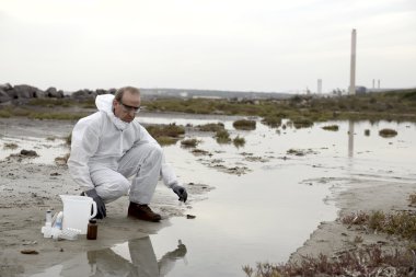 Worker in a protective suit examining pollution clipart