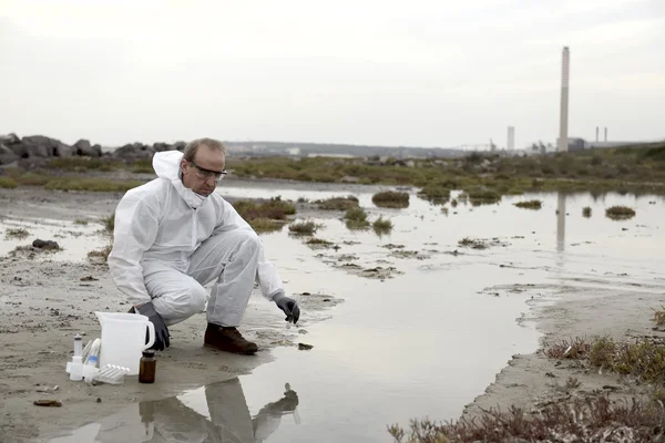 Worker in a protective suit examining pollution — Stock Photo, Image