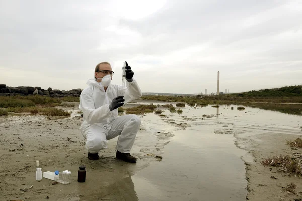 Worker in a protective suit examining pollution — Stock Photo, Image