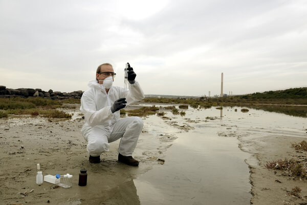 Worker in a protective suit examining pollution