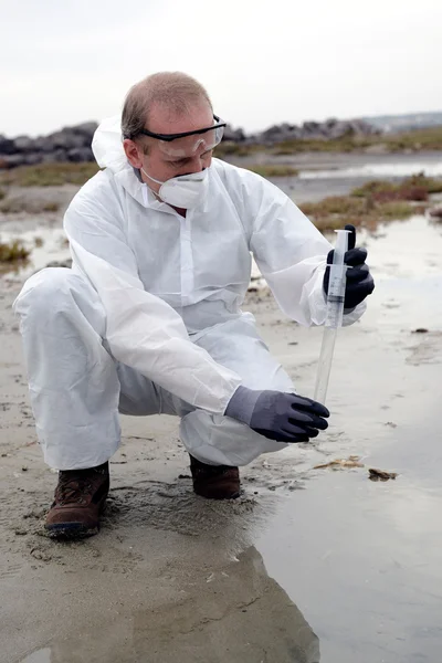 Worker in a protective suit examining pollution — Stock Photo, Image