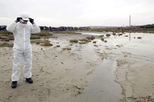 Worker in a protective suit examining pollution — Stock Photo, Image