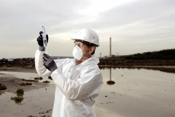 Trabalhador em um terno protetor que examina a poluição — Fotografia de Stock