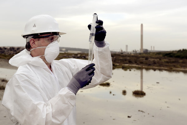 Рабочий в защитном костюме, изучающий загрязнение окружающей среды
