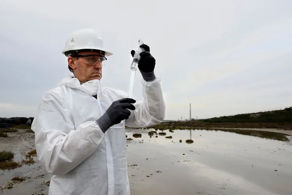 Travailleur en combinaison de protection examinant la pollution — Photo