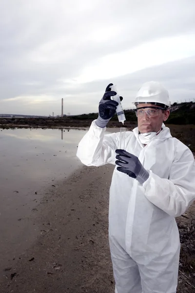 Worker in a protective suit examining pollution — Stock Photo, Image