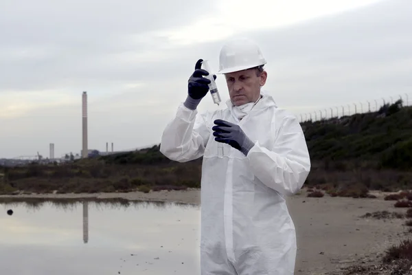 Worker in a protective suit examining pollution — Stock Photo, Image