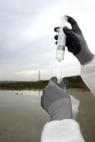 Worker in a protective suit examining pollution — Stock Photo, Image